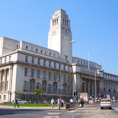 a large building with a clock tower on the side of it's face next to a street