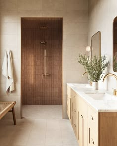 a bathroom with two sinks and a wooden bench in front of the shower area is shown