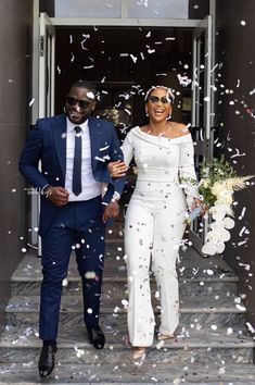 a man and woman are walking down the steps with confetti in front of them