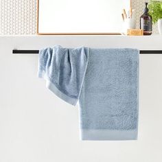 a blue towel hanging on the side of a white wall next to a bathroom mirror