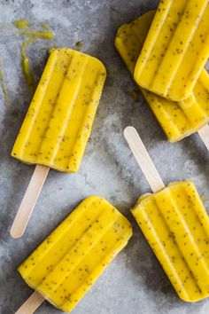 three popsicles with different toppings sitting on top of each other next to two wooden sticks