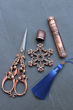 three different types of scissors and some tassels on a table with a blue tassel