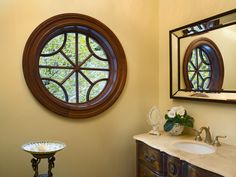 a bathroom with a sink, mirror and round window