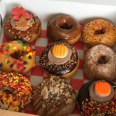 a box filled with lots of different flavored donuts on top of a checkered table