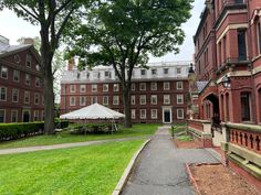 an old red brick building with a white tent in the middle and trees on both sides