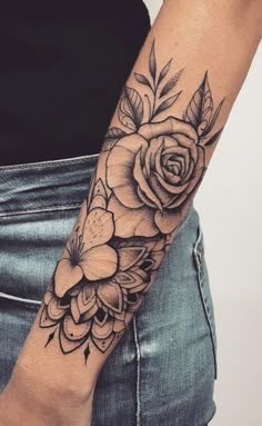 a woman's arm with flowers and leaves on it