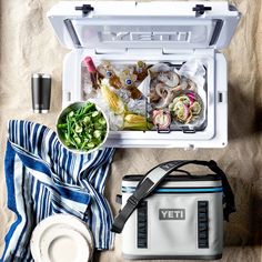 an open yeti cooler sitting on top of a sandy beach next to a towel