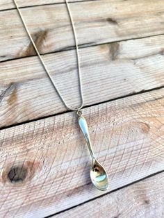 a silver spoon is hanging from a chain on a wooden table with wood planks