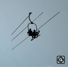 two people riding on a ski lift in the sky with wires attached to them,