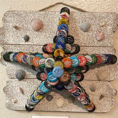 a starfish made out of beer bottle caps on a white wall with sea shells