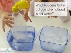 two plastic containers filled with water and ice are sitting on a table while a woman holds her hand over the container