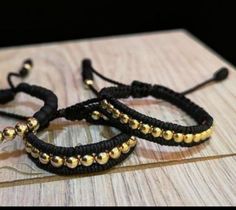 two black and gold beaded bracelets sitting on top of a wooden table next to each other