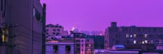 the city skyline is lit up at night with buildings in the foreground and purple sky