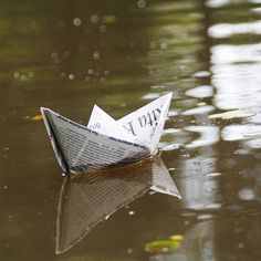 a paper boat floating on top of a body of water