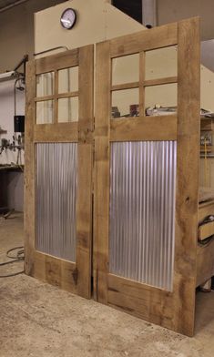 two wooden doors with glass panels in a workshop area, one open and the other closed