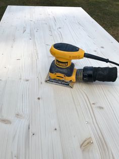 a sanding machine sitting on top of a white wooden table next to a pair of gloves