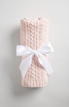 a pink blanket with a white bow on the front and back, wrapped in a light pink cable knit