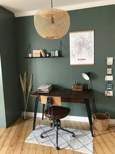 a home office with green walls and wood flooring in the corner, along with a hanging light fixture