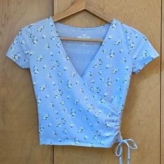 Nwt, Size Xs Light Blue With White Flowers Rouched Side With Tie Pit To Pit 16" Length 16" Cute Light Blue V-neck Top, Light Blue Fitted V-neck T-shirt, Cute Blue Tops For Spring, Light Blue Fitted T-shirt For Summer, Cute Light Blue Tops For Day Out, Fitted Light Blue T-shirt For Summer, Blue T-shirt For Spring, Fitted Light Blue Floral Print Tops, Blue Fitted T-shirt For Spring