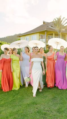 a group of women standing next to each other in dresses and holding white umbrellas