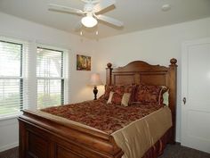 a bedroom with a bed, ceiling fan and two lamps on either side of the bed