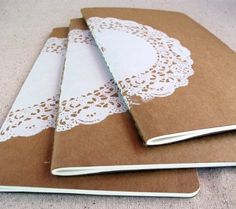 three brown notebooks with white doily on them