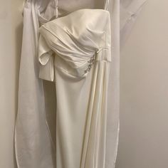 a white dress hanging on a wall with an open jacket over it and a tie around the neck