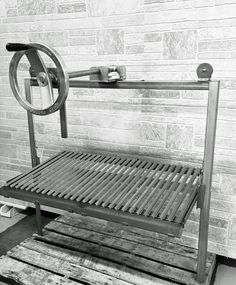 a metal bench sitting on top of a wooden pallet next to a brick wall