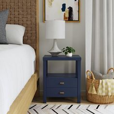 a blue nightstand next to a bed in a room with white curtains and a painting on the wall