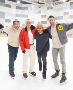 three men and one woman standing on an ice rink