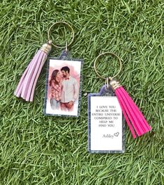 two keychains are laying on the grass with a photo and tassels