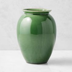 a green vase sitting on top of a white table