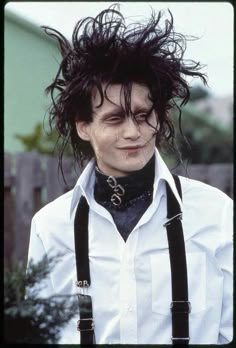 a man with black hair wearing suspenders and a white shirt