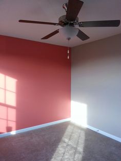 an empty room with a ceiling fan and red walls