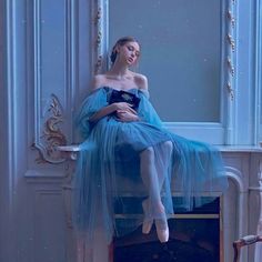 a woman in a blue dress sitting on top of a table