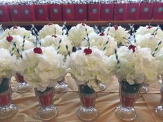 several vases filled with white and red flowers on top of a cloth covered table