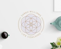 the logo for sarah williams life coaching is displayed on a table with flowers and teapots