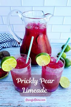 two glasses filled with pink lemonade and limes next to a pitcher of water