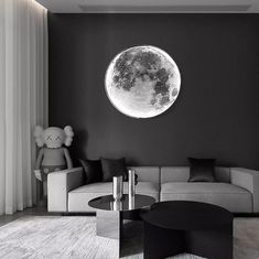 a living room with black and white furniture and a large moon on the wall above it