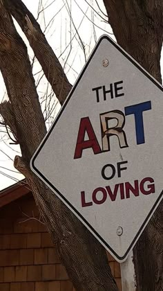 a sign that is hanging from the side of a tree in front of a house