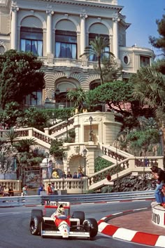 a man driving a race car in front of a large building