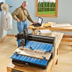 a man standing next to a machine in a room with blue walls and wooden floors