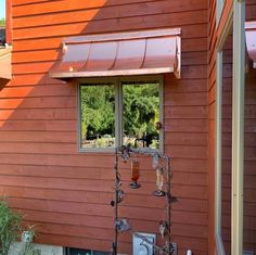 an orange house with two wine glasses on the window sill and a red awning