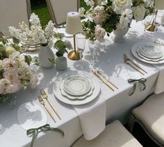 the table is set with white plates and flowers