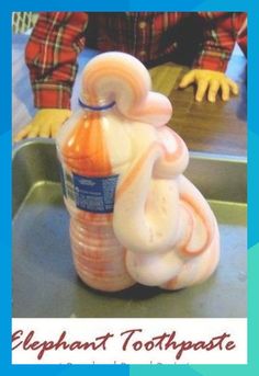 an elephant shaped toothpaste bottle sitting on top of a metal tray next to a child's hand