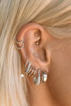 a woman with blonde hair wearing three ear cuffs and two piercings on her ears