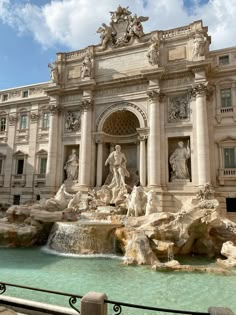 an ornate building with fountains and statues in front