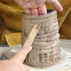 a person is making a vase out of clay