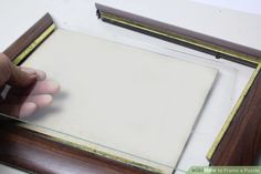 a person holding a piece of paper in front of a wooden frame with gold trim