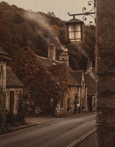 an old fashioned street light hanging from the side of a stone building with ivy growing on it's sides